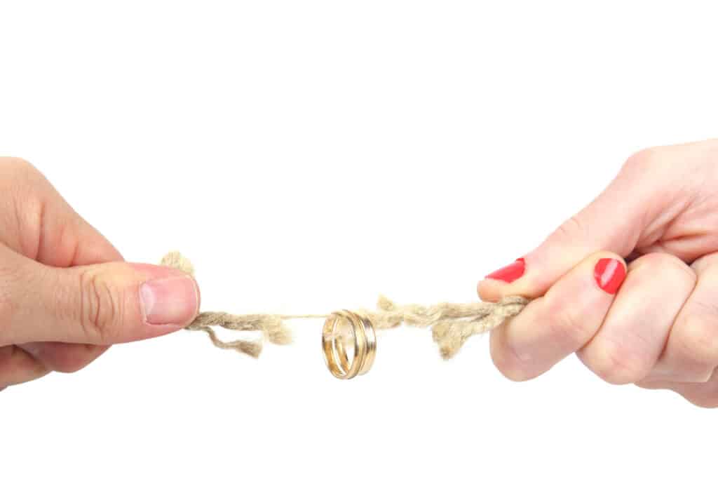A gold wedding ring suspended on a fraying rope, symbolising a marriage under strain and the decision to separate.